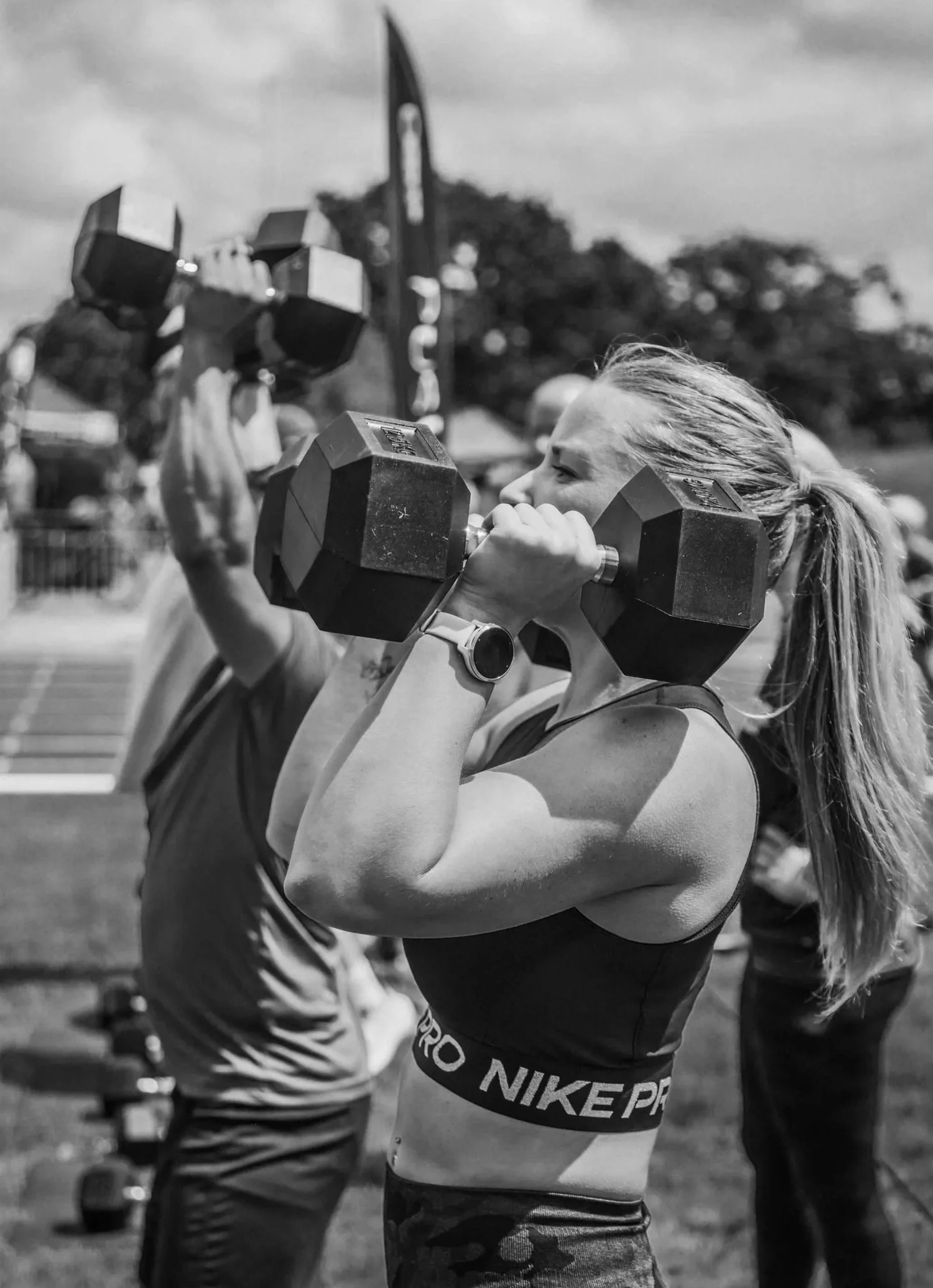 Atleta realizando un «push press» con dos mancuernas por encima de la cabeza labor